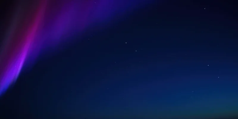 Sweeping aurora of purple and magenta across dark night sky