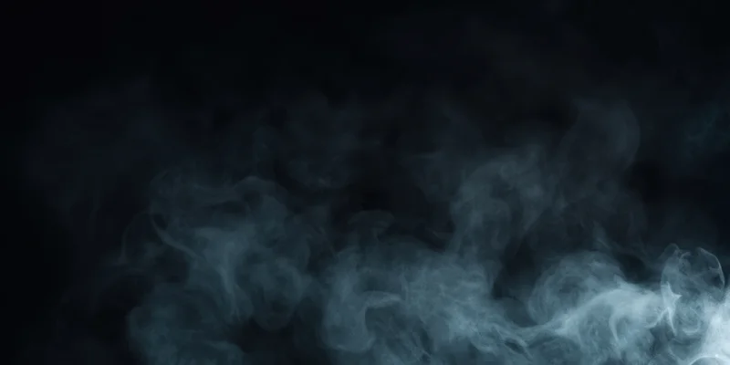 Dark plume of smoke drifting across black background with wispy vapor and copyspace
