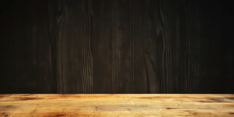 Warm worn light wood tabletop against dark seamless wooden backdrop with copyspace for product display