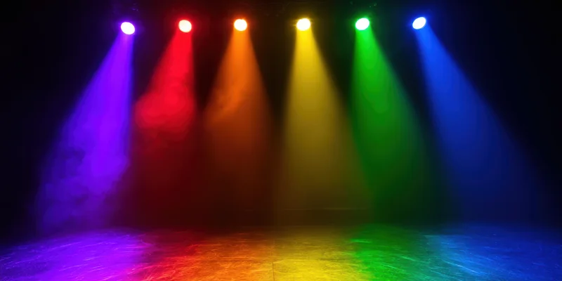 Six colored spotlights casting beams through smoke onto a dark stage floor