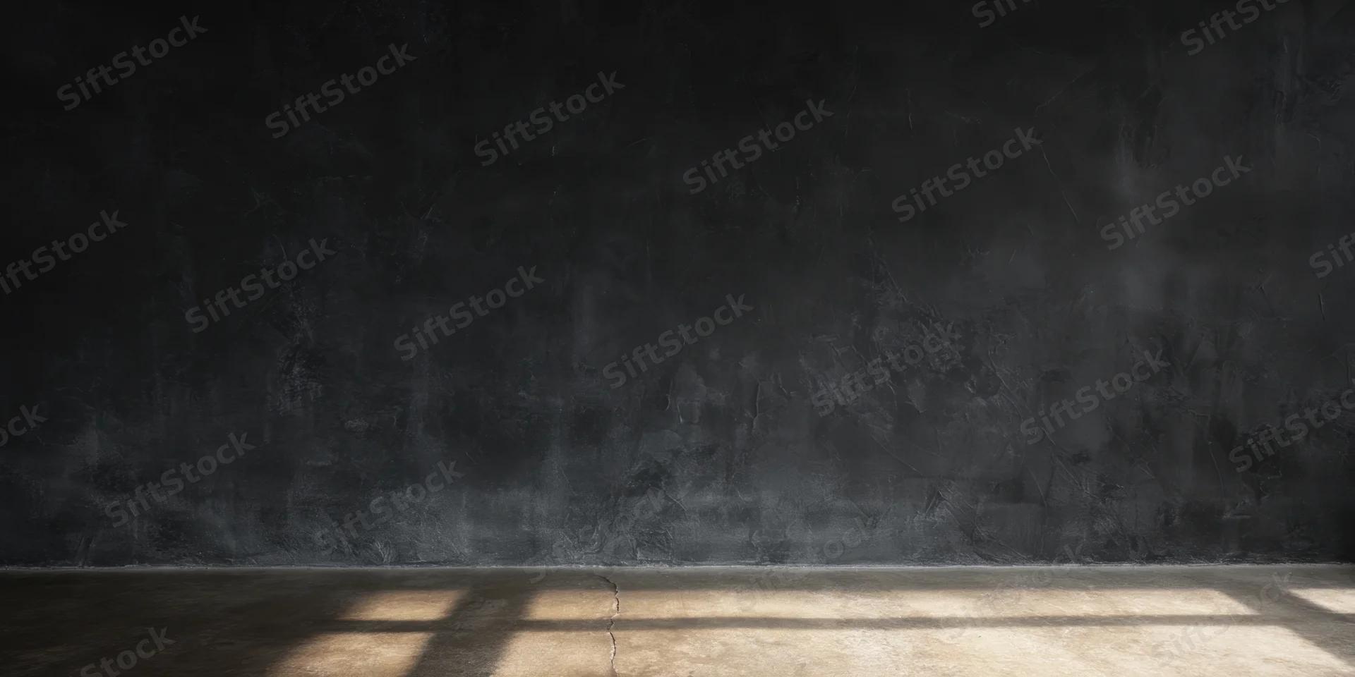 Empty dark studio interior with textured black wall and cracked concrete floor lit by slanted light beams