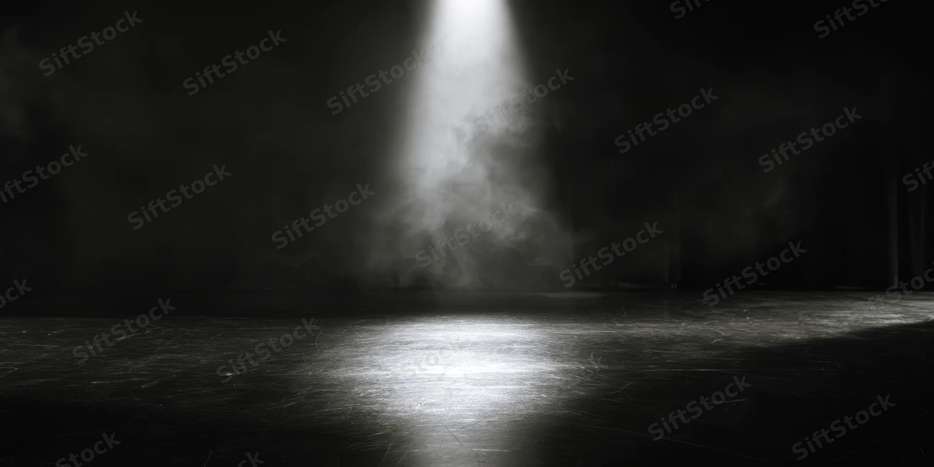Single spotlight illuminating empty stage floor in black and white theater setting