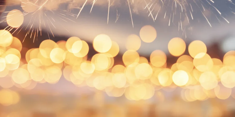Golden bokeh lights and fireworks in the night sky during a festive celebration