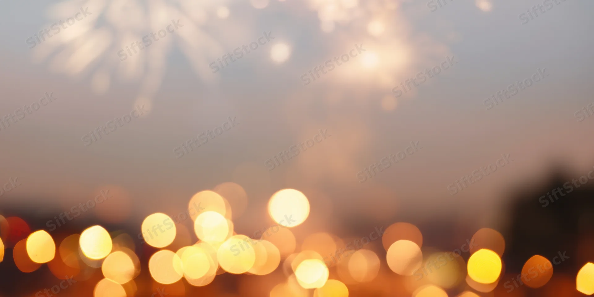 Warm golden bokeh lights and blurred fireworks over a city skyline at night