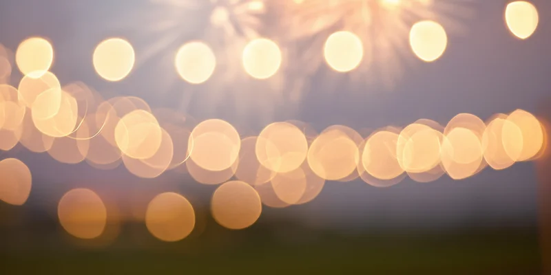 Warm golden bokeh lights arranged in strings against a blurred background with copyspace for festive celebration decoration