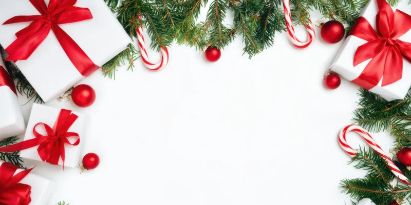 Christmas border with white gift boxes, red ribbons, pine branches, candy canes and ornaments arranged around a white copyspace