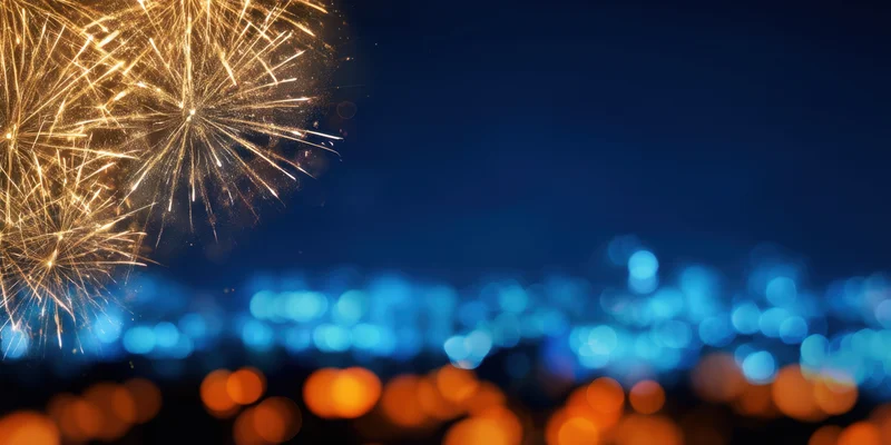 Golden fireworks exploding in night sky above blurred city lights