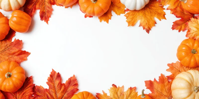 Small orange and white pumpkins with autumn leaves arranged in a frame on white background