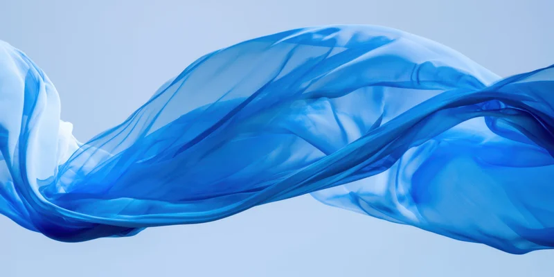 Flowing blue translucent fabric billowing in the air against a light background
