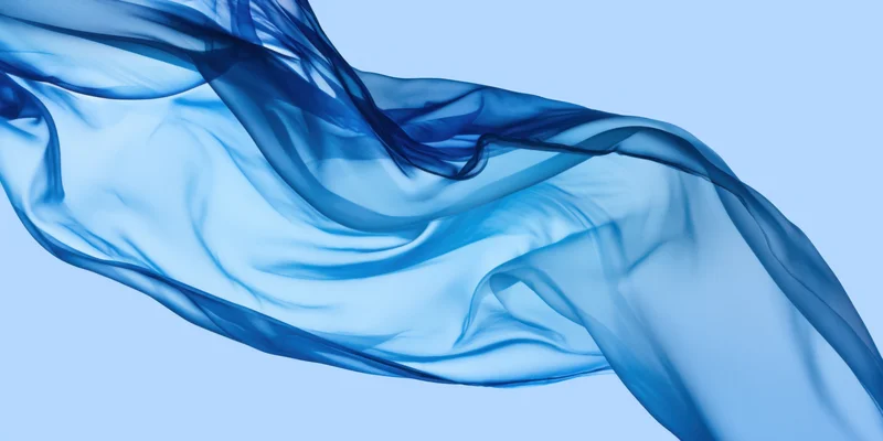 Flowing blue sheer fabric billowing in the air against a light blue background