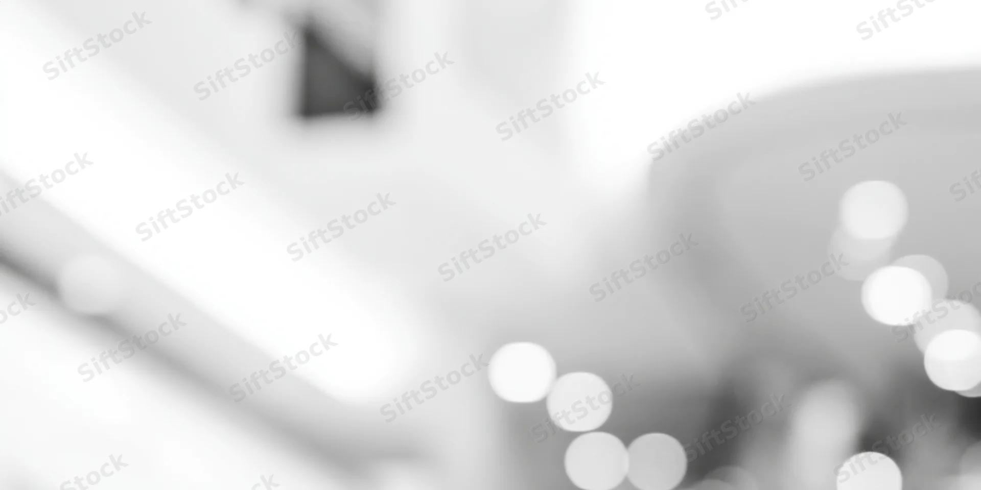 Blurred interior scene with soft glowing lights and high-key grayscale tones