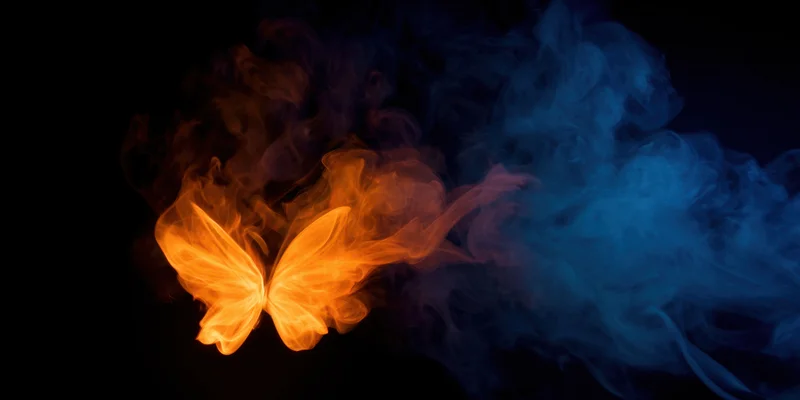 Luminous butterfly-shaped glow emerging from swirling orange and blue smoke against dark background