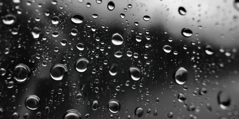 Water droplets clinging to a glass surface in macro closeup