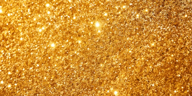 Gold glitter particles scattered across a surface in a macro closeup
