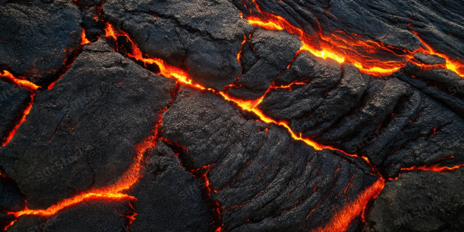 Glowing red lava flowing through cracks in black volcanic rock