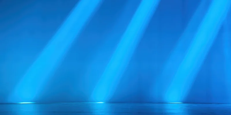 Diagonal blue light beams illuminating an empty stage floor