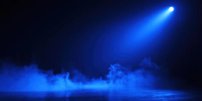 Blue spotlight beam cutting through thick fog over dark stage floor