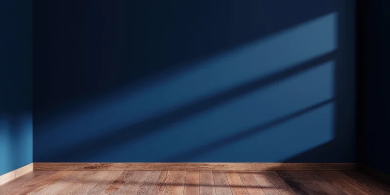 Empty room with deep blue wall and wooden floor showing sunlight shadows from a window