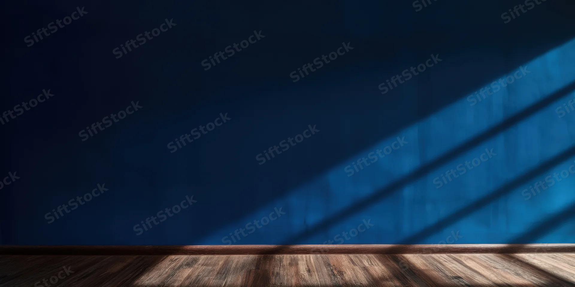 Empty room with deep blue wall and wooden floor lit by diagonal sunlight casting shadows