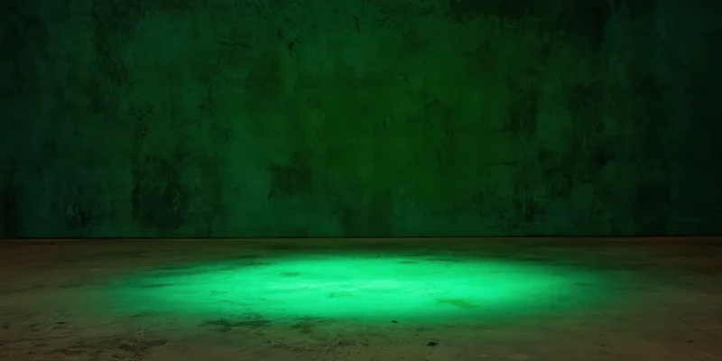 Green spotlight on concrete floor in dark textured studio space