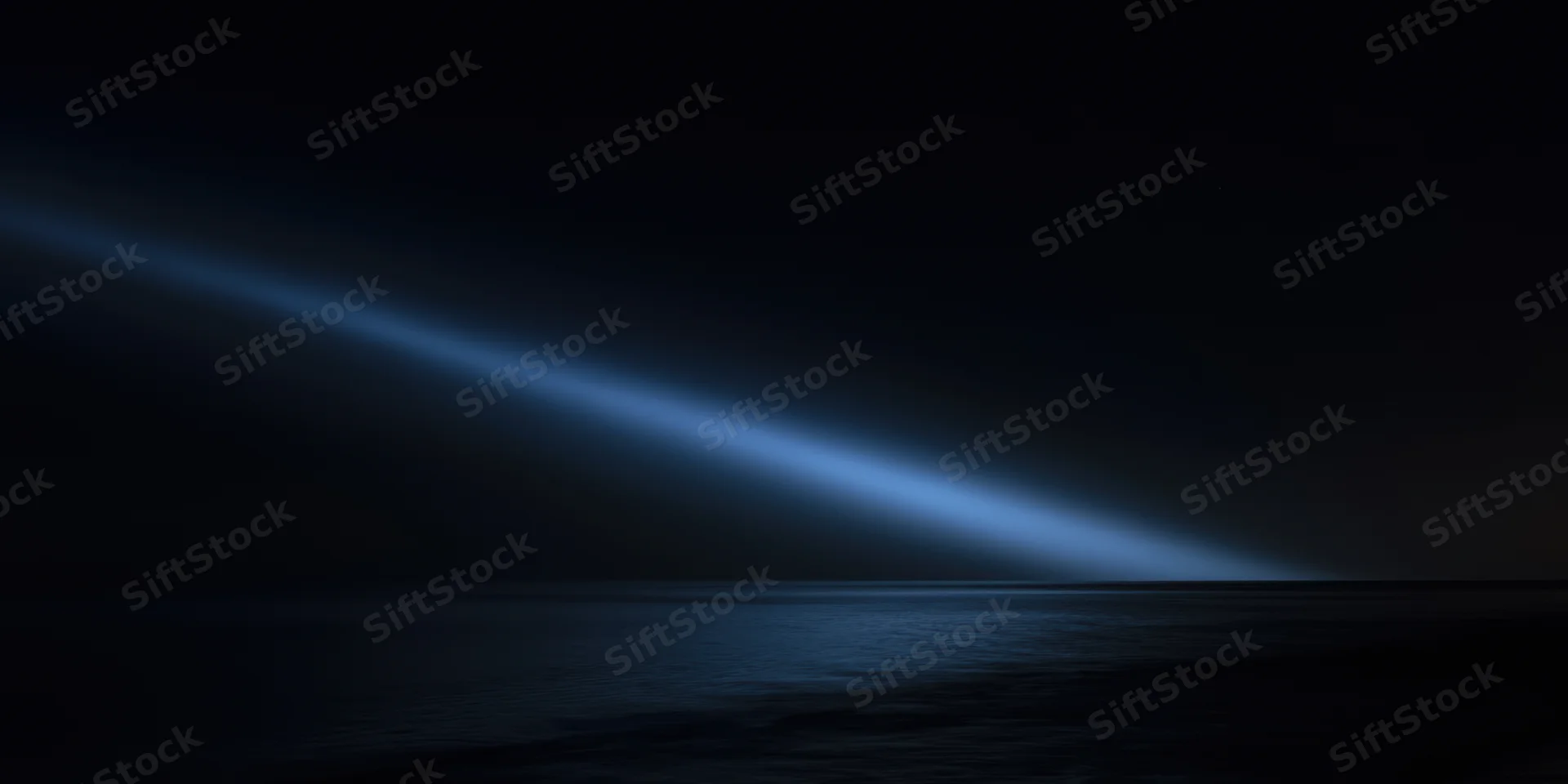 Diagonal blue light beam across dark night sea horizon