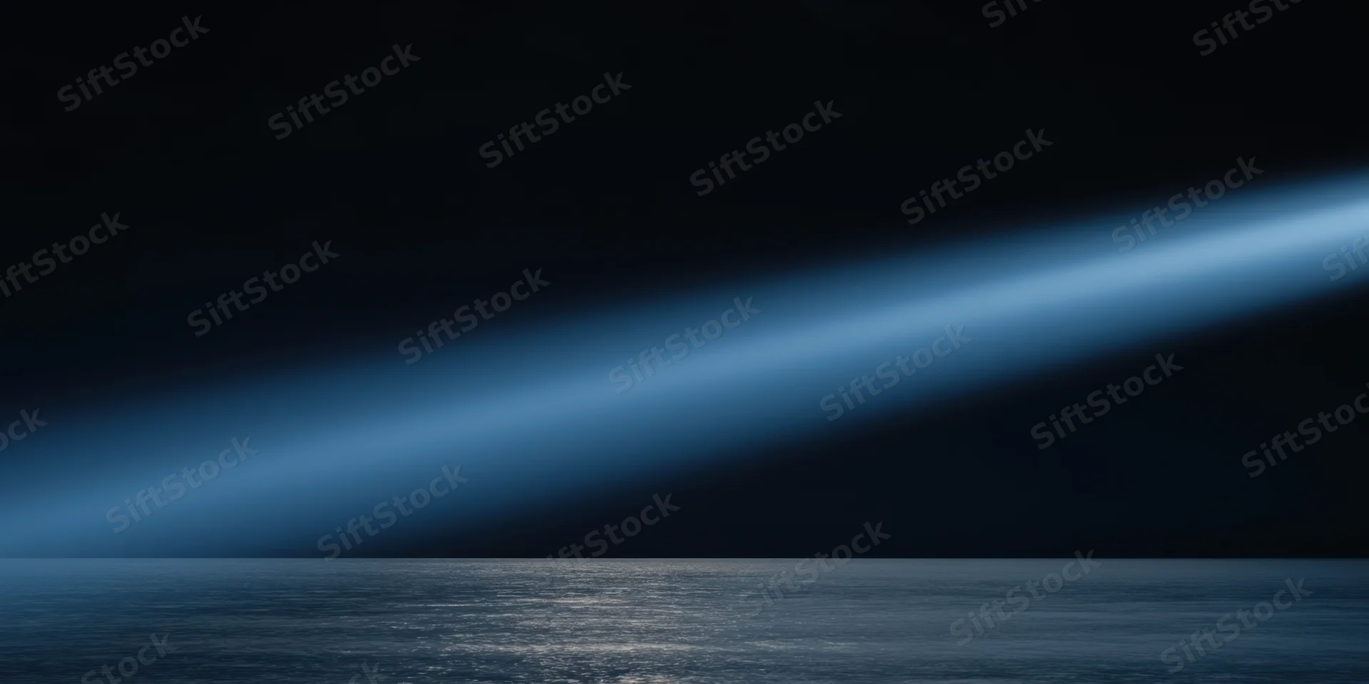 Diagonal blue light beam over calm ocean at night
