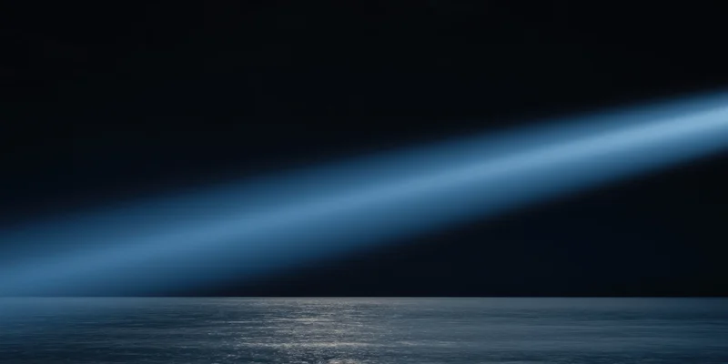 Diagonal blue light beam over calm ocean at night