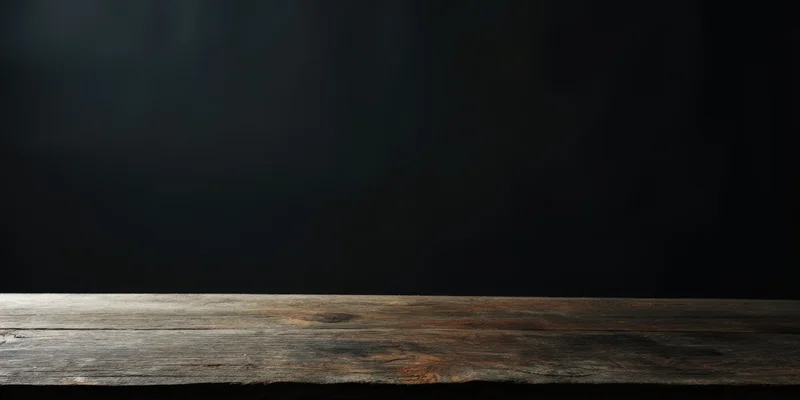 Weathered wooden table surface against dark studio wall with copyspace