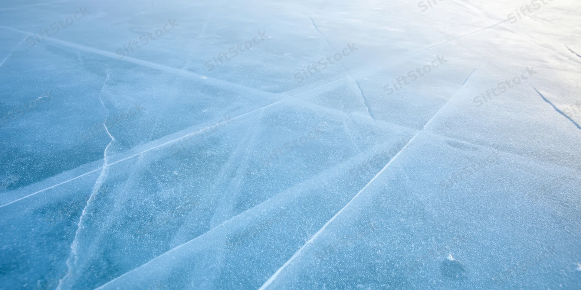Pale blue ice surface with intersecting cracks forming a network pattern