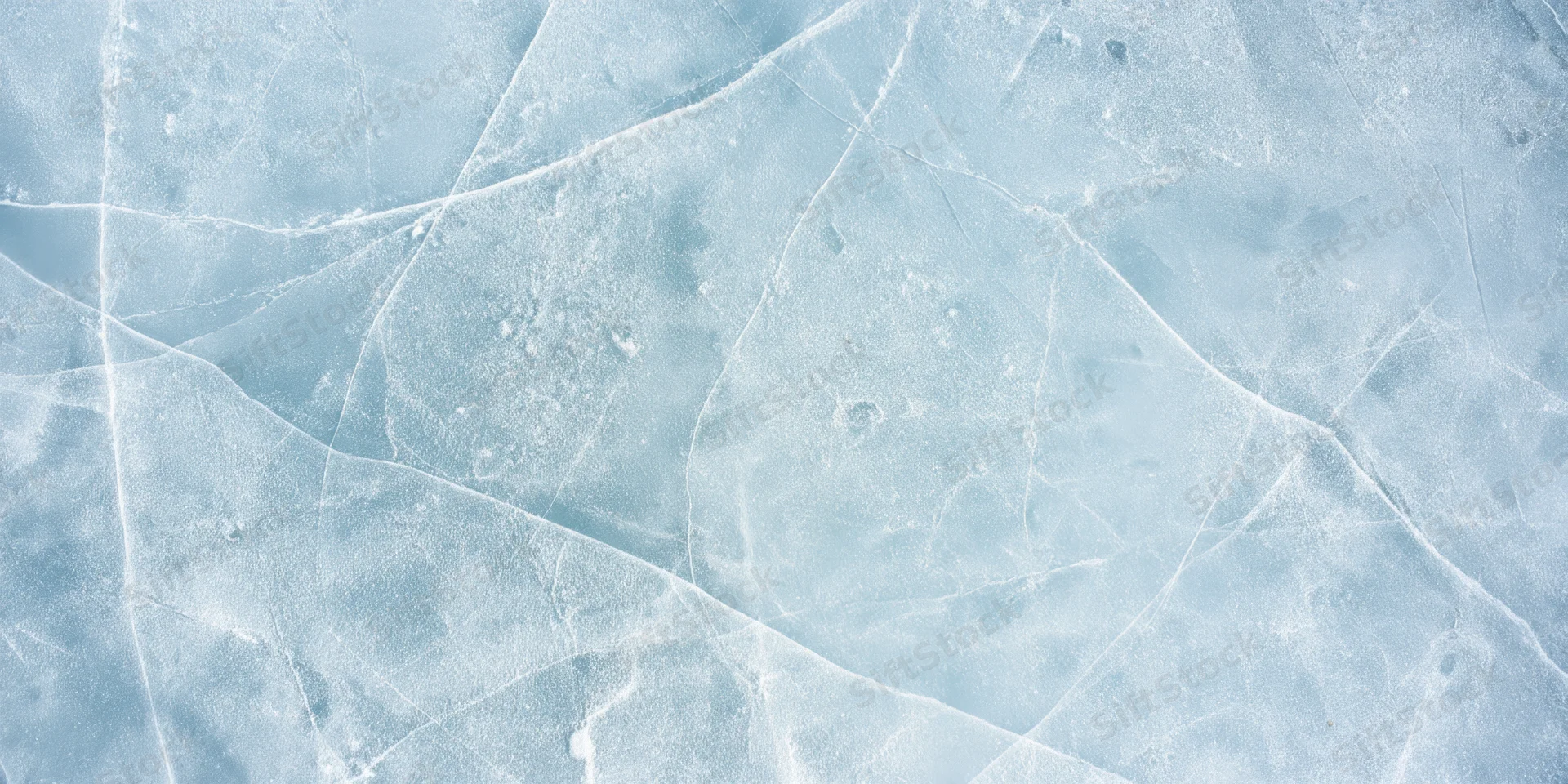 Pale blue ice surface with intersecting cracks and frost patterns