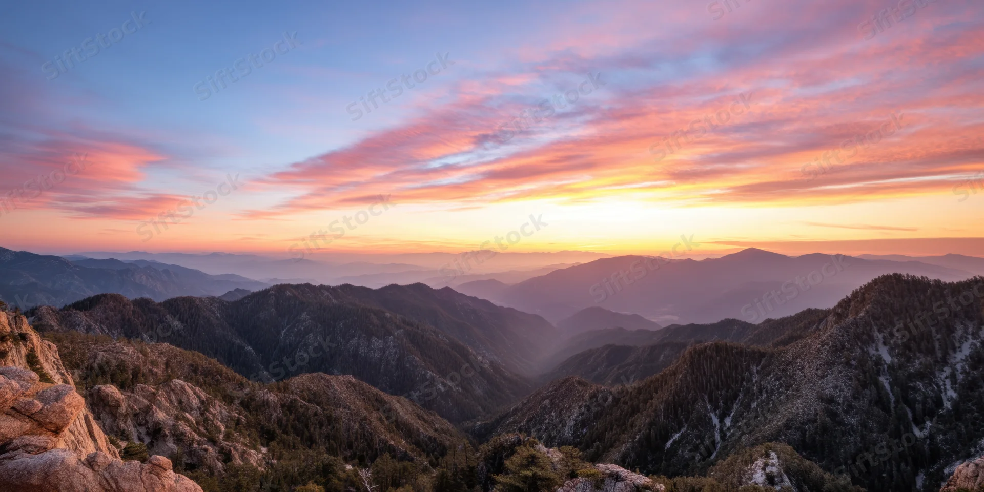 Panoramic sunrise over rugged forested mountains and rocky ridges in a mountain valley