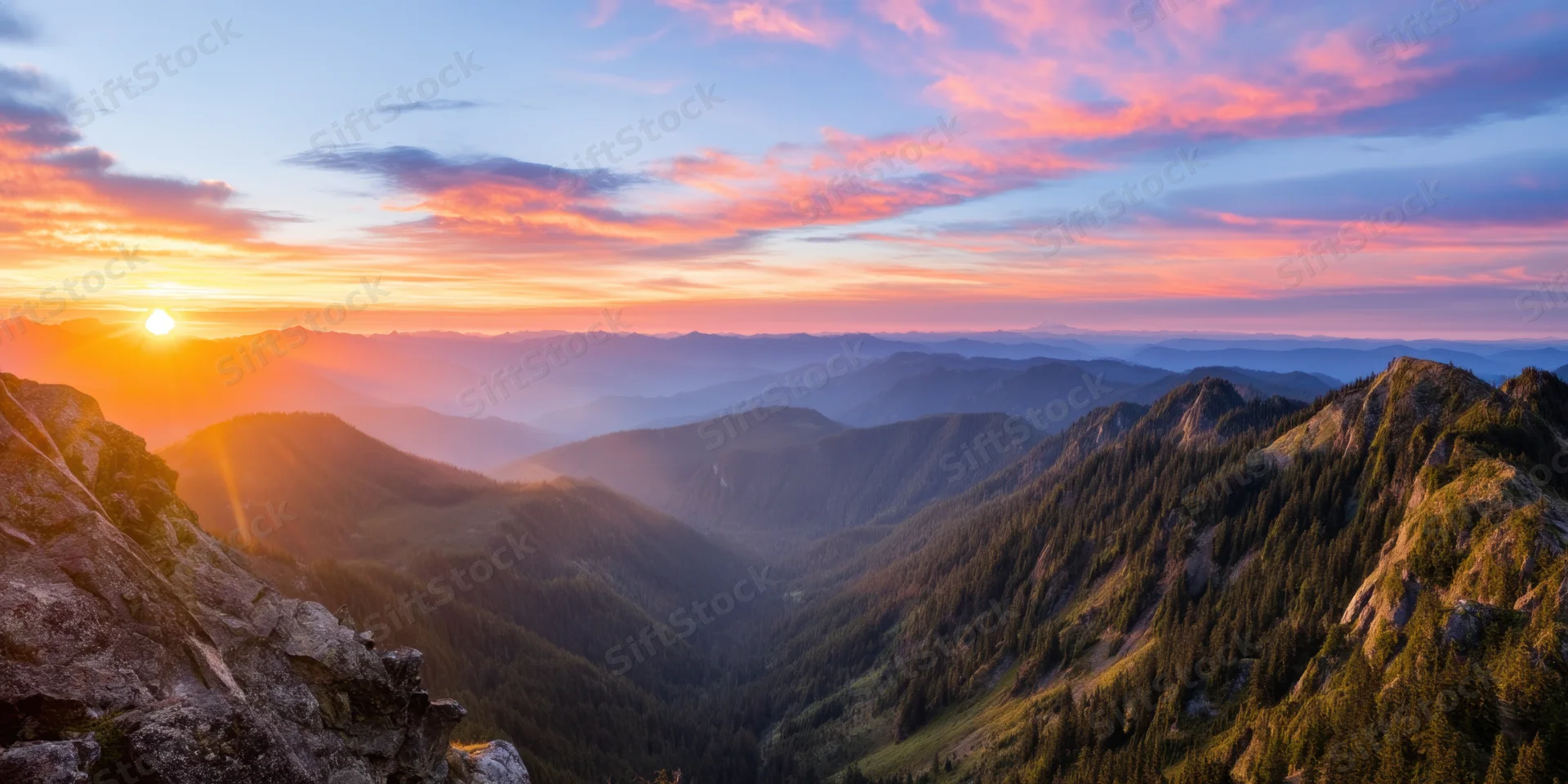 Panoramic sunrise over rugged forested mountains and rocky ridges in a deep valley