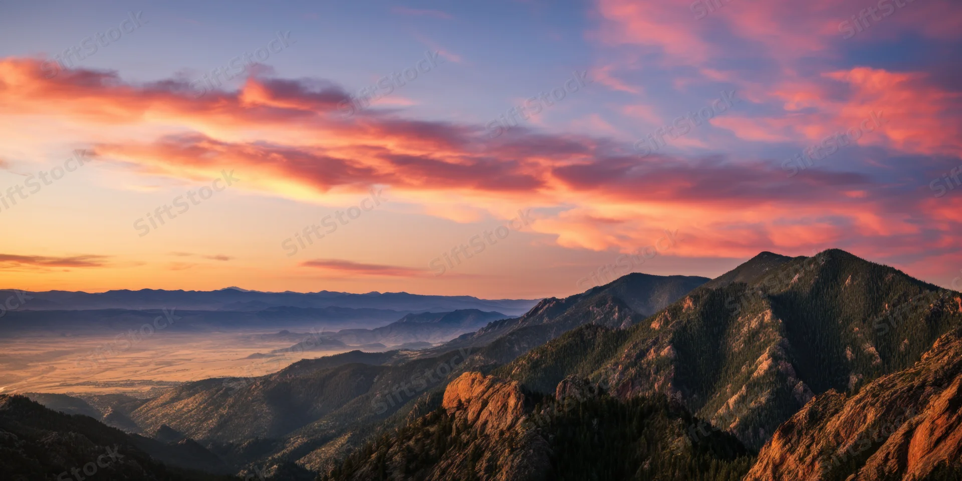 Panoramic sunrise over rugged forested mountains and rocky terrain with layered valleys below
