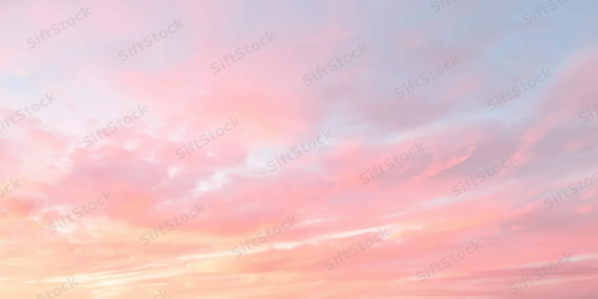 Pastel sky with soft fluffy clouds in pink peach and pale blue at sunrise or sunset