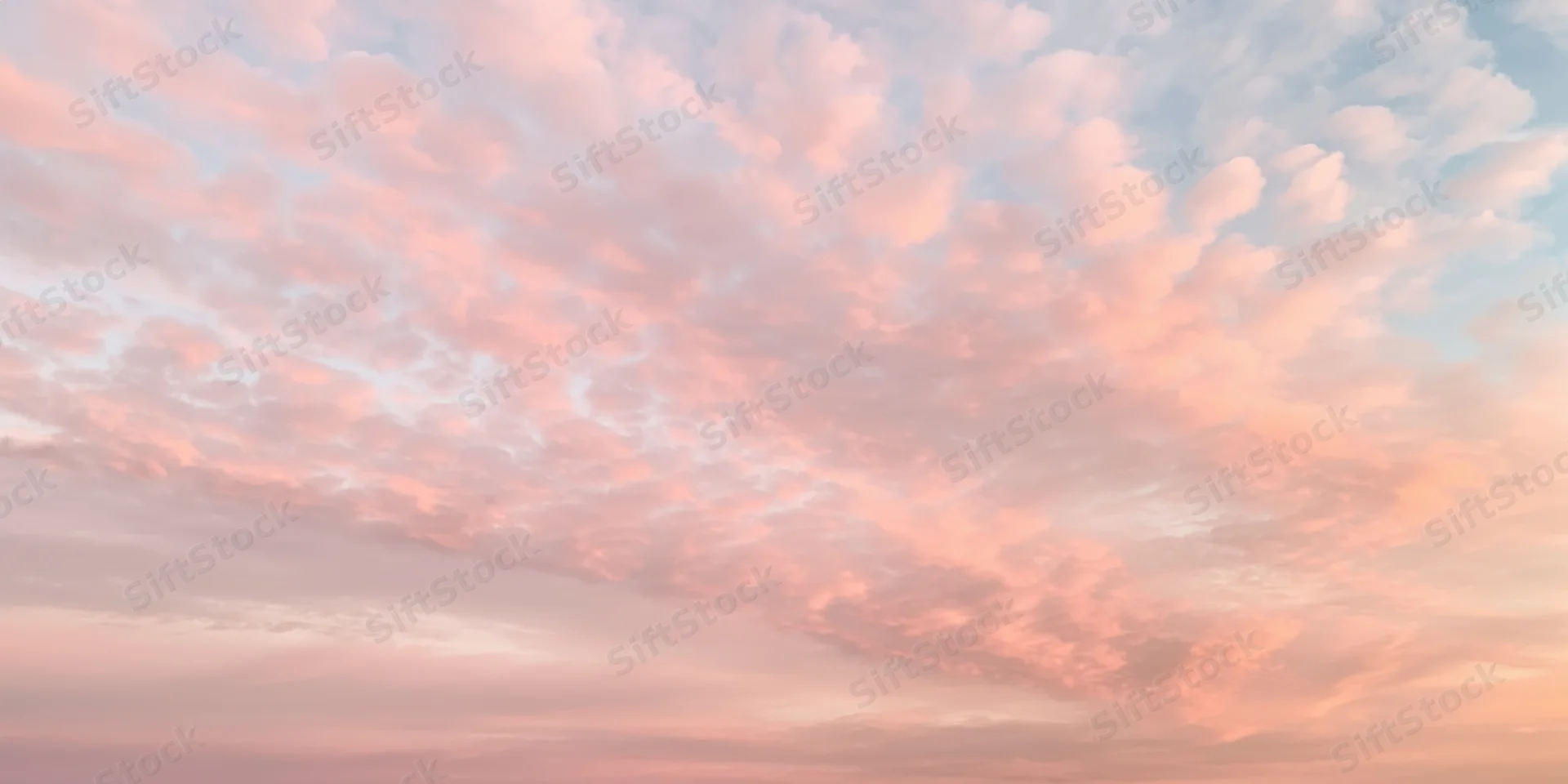 Pastel sky with soft fluffy clouds in pink and peach hues at dawn or dusk