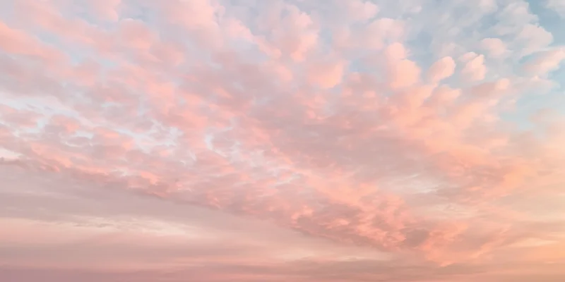 Pastel sky with soft fluffy clouds in pink and peach hues at dawn or dusk