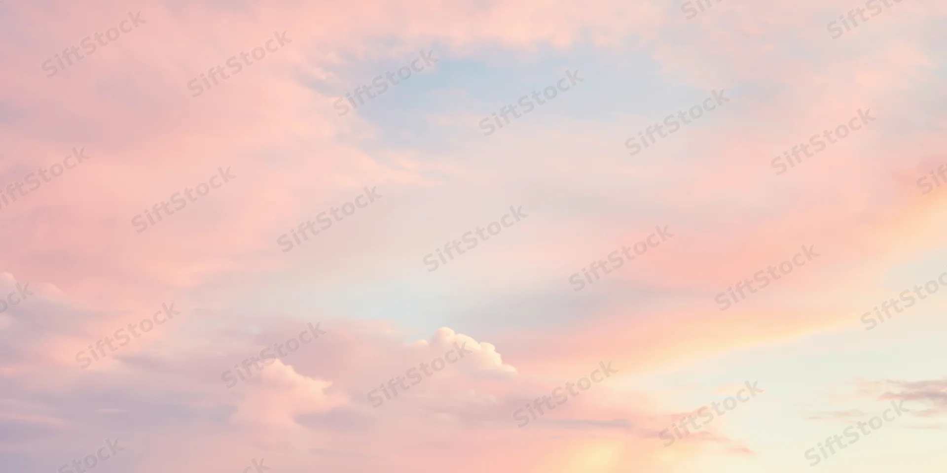 Pastel sky with soft fluffy clouds in pink peach and pale blue hues at twilight