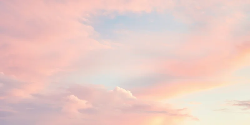 Pastel sky with soft fluffy clouds in pink peach and pale blue hues at twilight