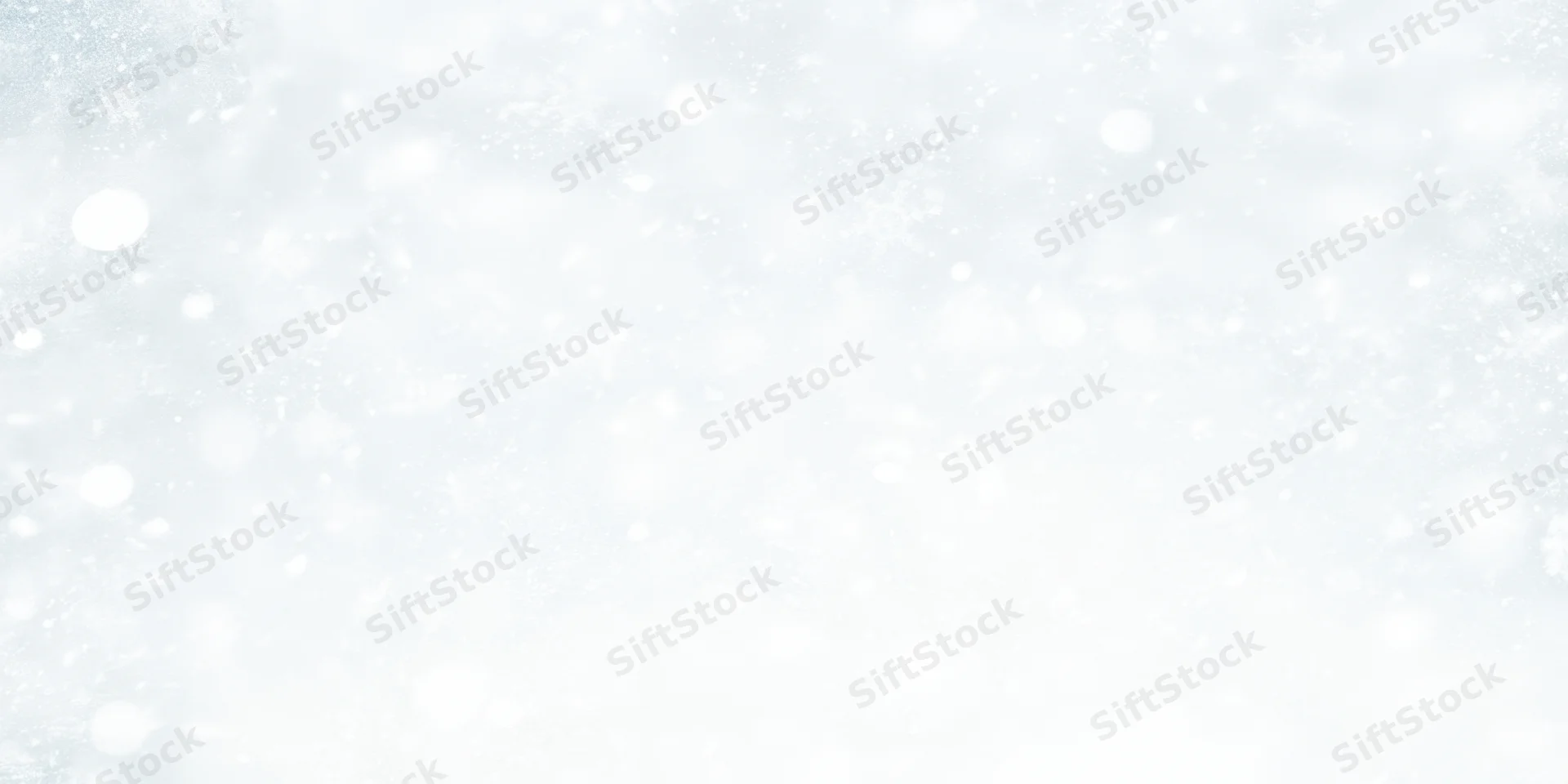 Soft snowfall drifting across a white winter background with blurred bokeh and copyspace