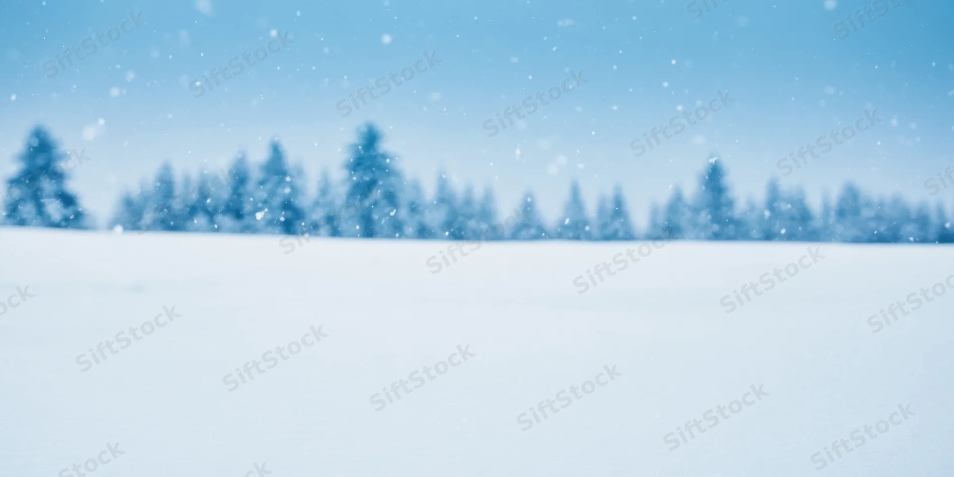 Snow-covered field under pale blue sky with distant trees in winter landscape