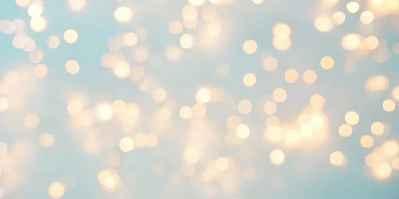 Warm fairy lights in soft bokeh against a pale blue background