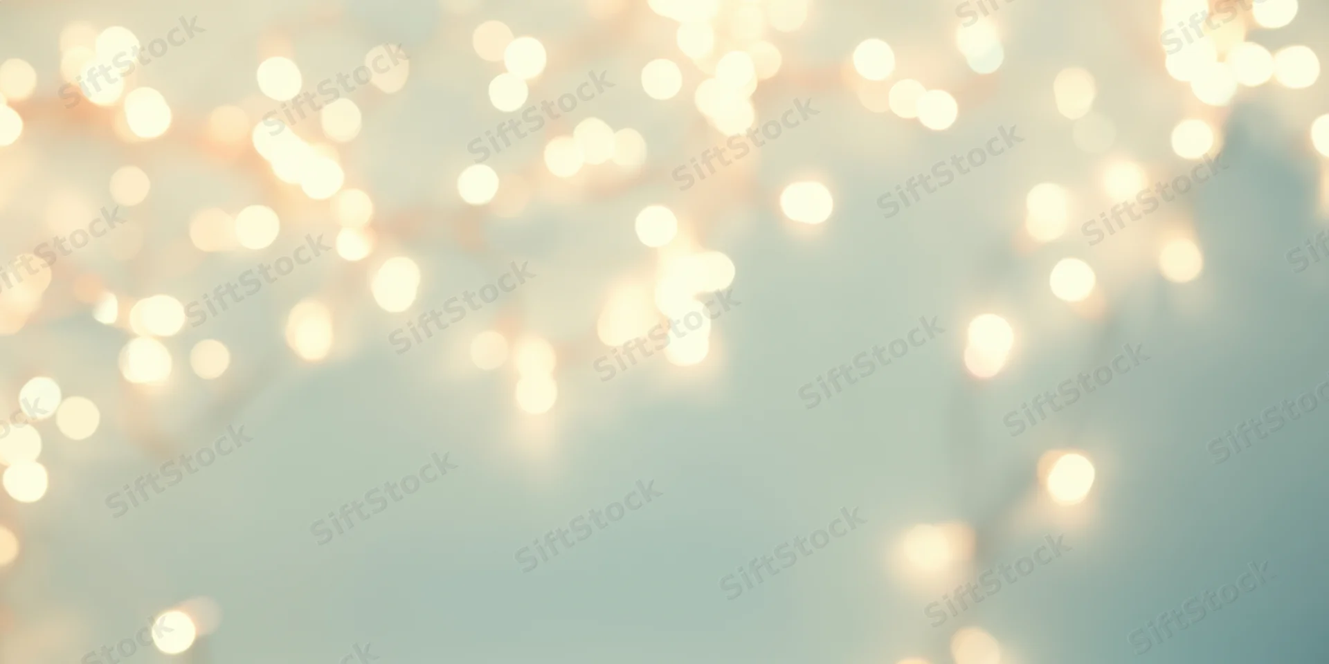 Warm fairy lights in soft bokeh against a pale blue background with copyspace