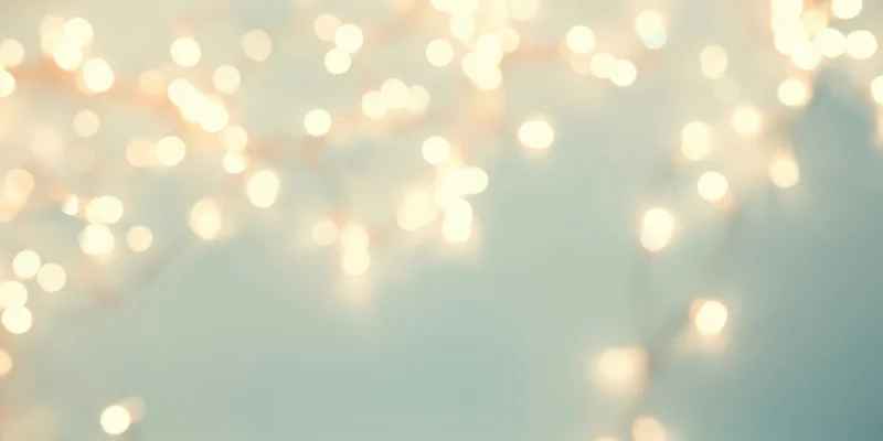 Warm fairy lights in soft bokeh against a pale blue background with copyspace