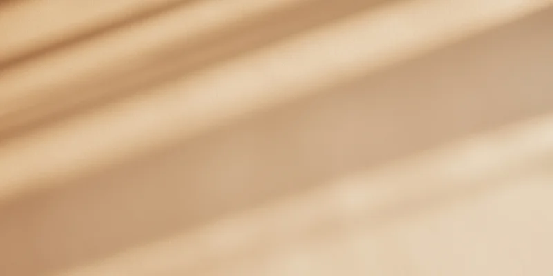 Soft beige surface with diagonal bands of sunlight and shadow
