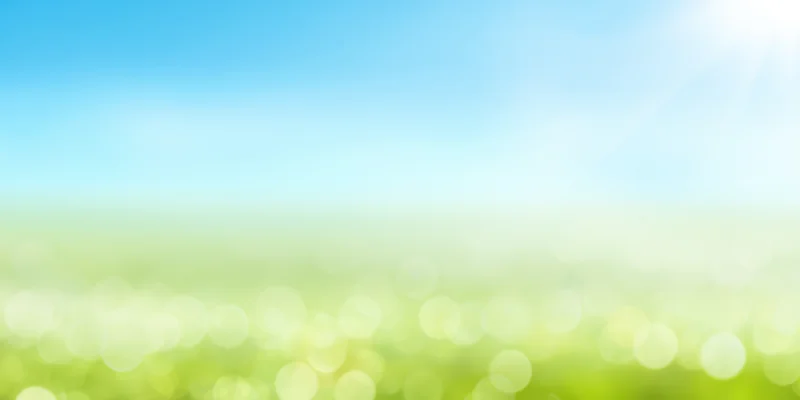 Soft sunlit gradient landscape with bright blue sky fading into green field and bokeh lights