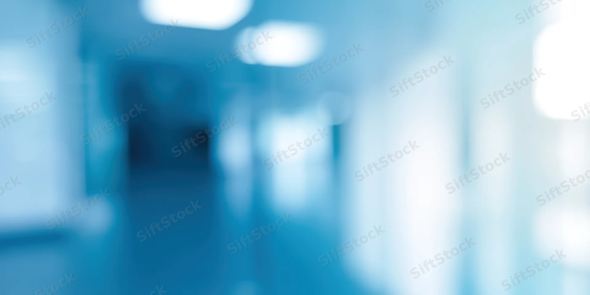 Blurred view of an empty office hallway with cool blue lighting and soft focus