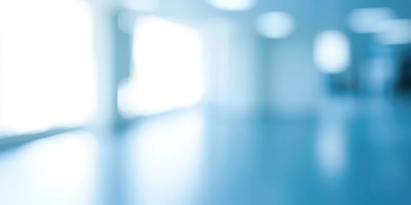 Blurred empty office hallway with cool blue tones and reflections on the floor