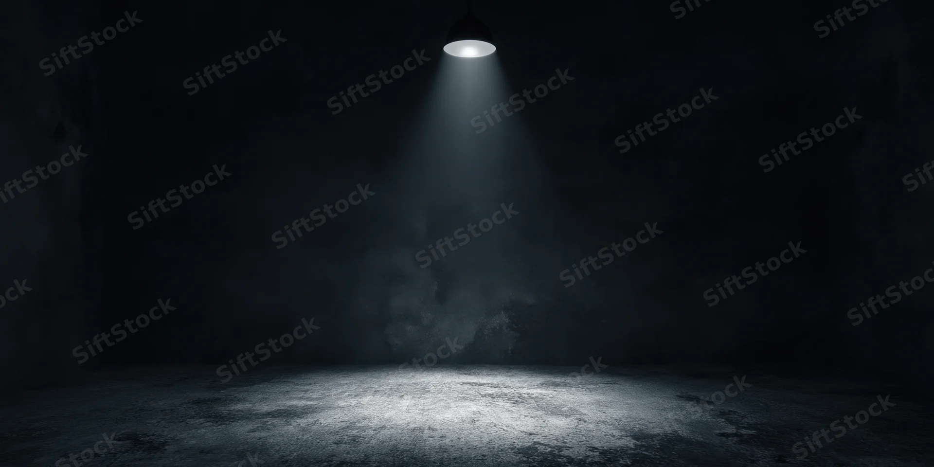 Empty stage illuminated by a single overhead spotlight in a dark industrial room