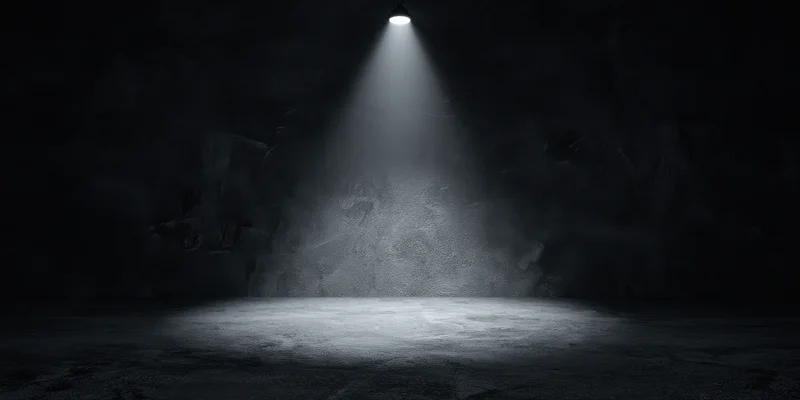Empty stage illuminated by a single overhead spotlight in a dark theater interior