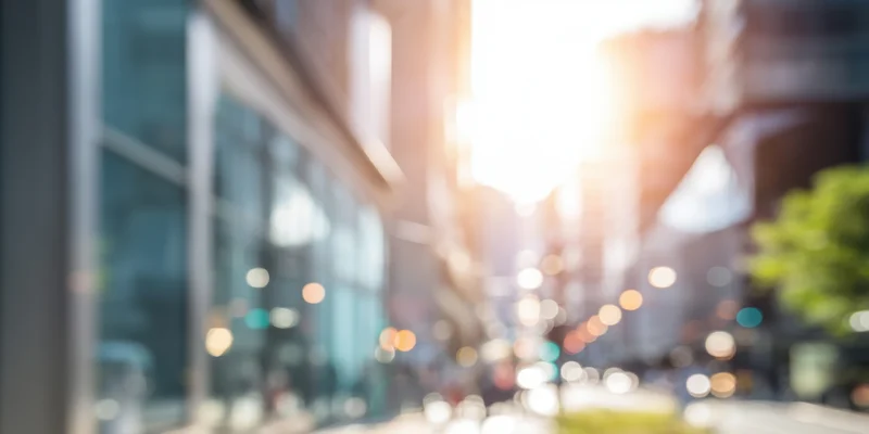 Sunlit urban street with glass-fronted buildings and soft bokeh lights in the background